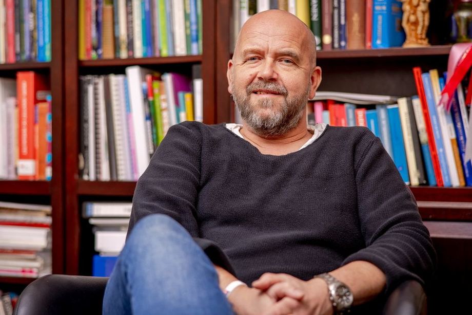 Thomas J. Winther photographed in front of his bookshelf
