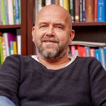 Thomas J. Winther photographed in front of his bookshelf